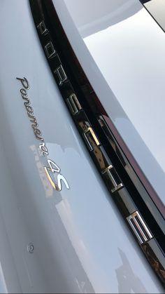 the front end of a white sports car with chrome lettering on it's side