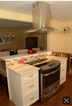 a kitchen with an oven, stove and dining room table in the backround