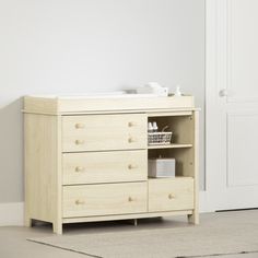 a baby changing table in a room with white walls and rugs on the floor