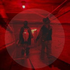 two people standing in a tunnel with red light