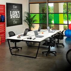 an office area with desks, laptops and exercise balls