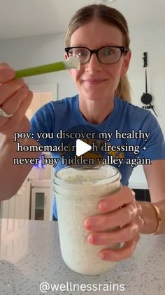 a woman is holding a spoon in her hand while she holds a jar with food inside