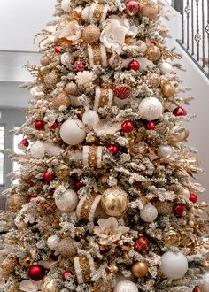 a white christmas tree with gold and red ornaments