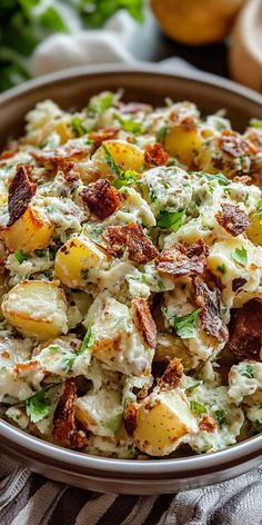 potato salad with bacon and parsley in a bowl on a striped cloth next to bread