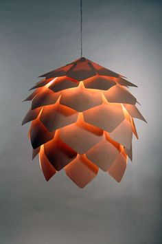 an orange light hanging from a ceiling in front of a gray background with the lights turned on