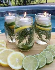 three mason jars filled with lemons, rosemary and water next to sliced limes