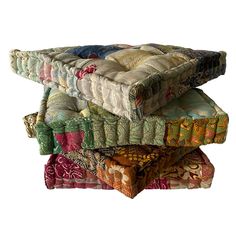 four pillows stacked on top of each other in different colors and patterns, all piled together