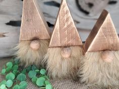 three small wooden gnomes with long hair on top of a burlied cloth