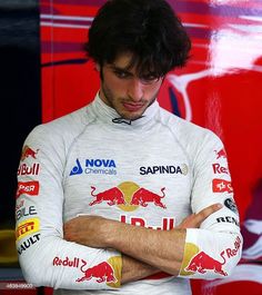 a man standing in front of a red bull sign with his arms crossed and looking down