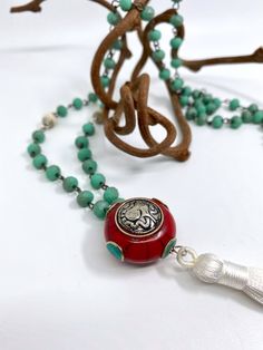 "This Tibetan pendant has a silver Ganesh on a red coral pendant with inlaid turquoise details. The chain is turquoise rosary bead chain and joined with white vintage mosaic Tibetan beads, finished with a white silk tassel. - The necklace is 32\" long - The charm is 1.25\" in diameter - White silk Tassel is 4\" long * * * * * * * Connect with WTB on social media! Instagram: @whatthebuckle Facebook: What the Buckle Twitter: @Whatthebuckle" Hand-strung Turquoise Necklaces With Round Beads, Turquoise Rosary, Bohemian Long Turquoise Necklace Hand-strung, Hand-strung Spiritual Turquoise Necklace With Round Beads, Hand-strung Turquoise Necklace With Sterling Silver Round Beads, Vintage Mosaic, Bohemian Turquoise Tassel Necklace (adjustable), Coral Pendant, Coral And Gold