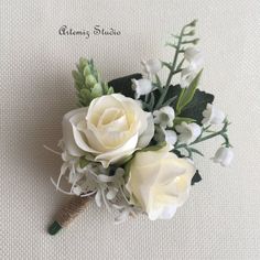 a boutonniere with white flowers and greenery