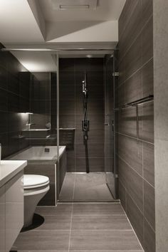 a bathroom with a toilet, sink, and shower stall in black and white colors