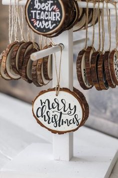 wooden ornaments hanging from a white stand with merry christmas signs on it's sides