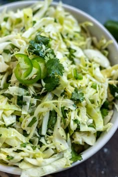 a white bowl filled with coleslaw and cucumber garnishments