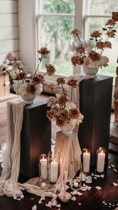 flowers and candles are arranged in vases on the floor