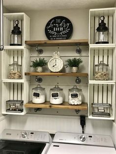 a white washer and dryer sitting in a room next to shelves with clocks on them