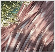 pink and silver sheer fabric next to a tree with green leaves in the foreground