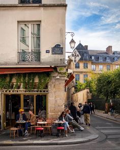 people sitting at tables in front of a building