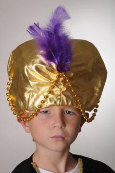 a young boy wearing a gold hat with purple feathers