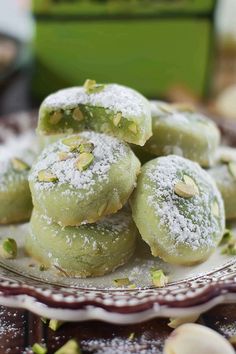 some powdered sugar covered doughnuts on a plate with pistachio sprinkles