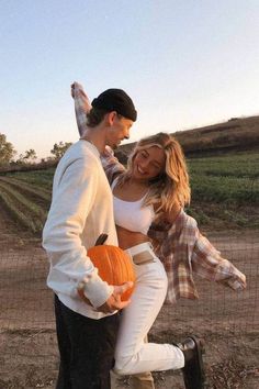 a man and woman dressed up in costumes, one holding a pumpkin while the other is dancing