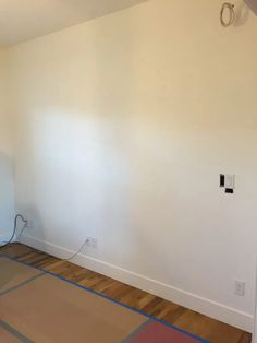 an empty room with hard wood flooring and white walls in the corner is being painted