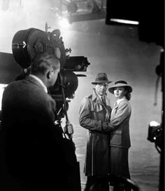 black and white photograph of two men standing in front of a camera with their arms crossed