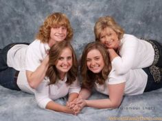 three women laying on the ground posing for a photo together with their arms around each other