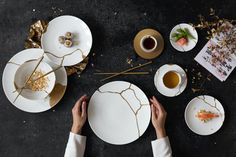 two hands are holding plates with food on them, while another person holds a cup and saucer