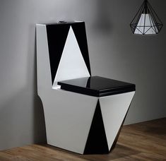 a black and white toilet sitting on top of a wooden floor next to a lamp