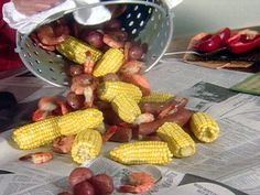 a person is scooping corn on the cob from a colander onto newspaper