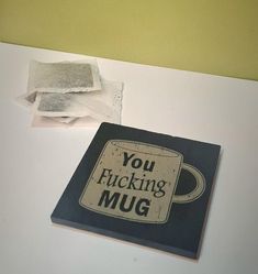 a coffee mug sitting on top of a white counter next to a piece of paper