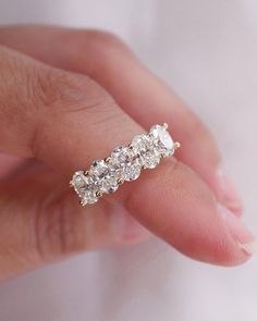 a woman's hand holding a ring with three stones