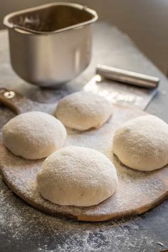 four uncooked doughnuts sitting on top of a wooden board