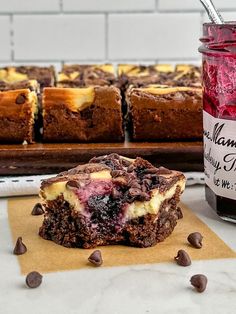 a close up of a dessert near a jar of jelly and some brownies on a table