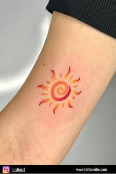 a sun tattoo on the arm with red and yellow colors in the shape of a spiral