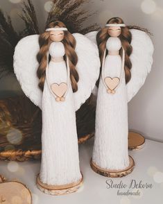 two angel figurines sitting on top of a table next to some dried grass