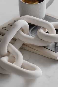 a coffee cup sitting on top of a book next to a pair of white links