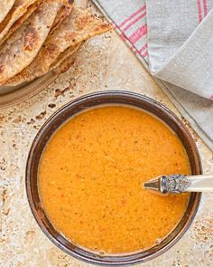 a bowl of soup with pita bread on the side