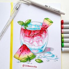 a watermelon drink in a glass with ice and mint on the rim next to markers