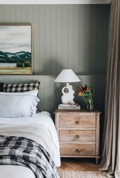 a bed sitting next to a nightstand with a lamp on top of it in a bedroom