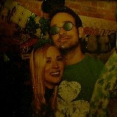 a man and woman are posing for a photo in front of a wall with mickey ears on it