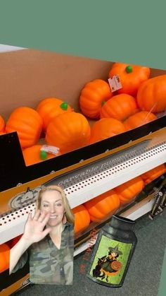 a woman standing in front of a display of pumpkins at a store with her hands up