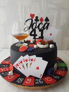 a birthday cake decorated with playing cards, dices, and whiskey on a table