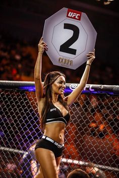 a woman holding up a sign in front of a fence with the number 2 on it