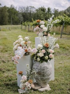 two vases with flowers are sitting in the grass