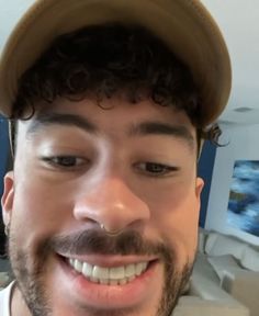 a close up of a person wearing a hat and looking at the camera with a smile on his face