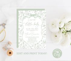 a white and green wedding card on top of a table next to some baby flowers