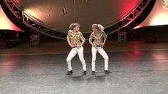 two people are performing on stage in white pants