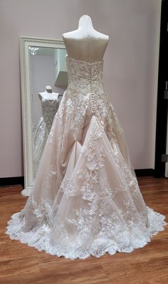 a wedding dress on display in front of a mirror